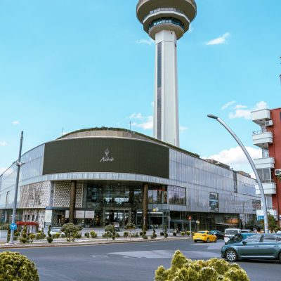 Bright daytime view of Atakule Tower and Shopping Mall with vibrant flowers in the foreground.